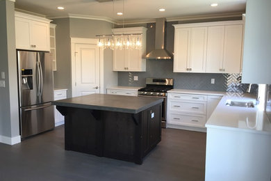 Mid-sized transitional l-shaped dark wood floor and brown floor kitchen photo in San Diego with a double-bowl sink, shaker cabinets, white cabinets, solid surface countertops, gray backsplash, ceramic backsplash, stainless steel appliances and an island