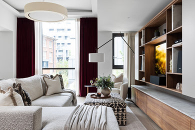 This is an example of a large modern open plan living room curtain in London with white walls, light hardwood flooring, a wall mounted tv and a coffered ceiling.