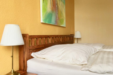 Kleines Hauptschlafzimmer mit gelber Wandfarbe, Vinylboden und braunem Boden in Dortmund