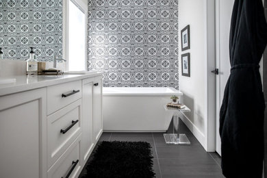 This is an example of a mid-sized modern master bathroom in Other with recessed-panel cabinets, grey cabinets, a freestanding tub, an alcove shower, grey walls, porcelain floors, a drop-in sink, engineered quartz benchtops, black floor and white benchtops.