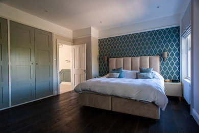 Large modern master bedroom in London with blue walls, dark hardwood flooring and brown floors.