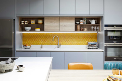 This is an example of a large contemporary eat-in kitchen in London with flat-panel cabinets, grey cabinets, quartzite benchtops, yellow splashback, ceramic splashback, with island and white benchtop.