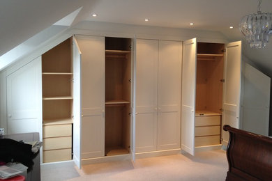 This is an example of a contemporary wardrobe in Cambridgeshire with flat-panel cabinets, white cabinets and carpet.