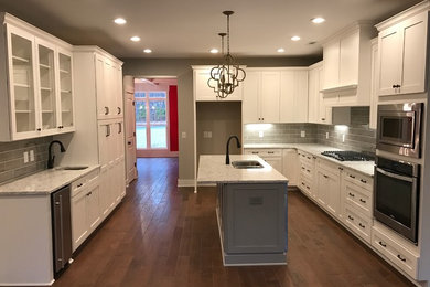 Enclosed kitchen - mid-sized traditional l-shaped dark wood floor and brown floor enclosed kitchen idea in Atlanta with a double-bowl sink, shaker cabinets, white cabinets, granite countertops, gray backsplash, ceramic backsplash, an island and stainless steel appliances