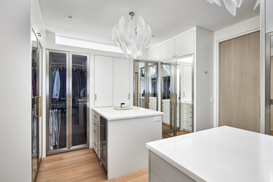 Mid-sized transitional gender-neutral medium tone wood floor and beige floor walk-in closet photo in Ottawa with flat-panel cabinets and white cabinets