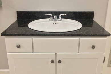 Bathroom - mid-sized traditional bathroom idea in Miami with a drop-in sink, flat-panel cabinets, white cabinets, granite countertops and white walls