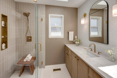 Transitional gray tile gray floor and single-sink corner shower photo in Seattle with flat-panel cabinets, light wood cabinets, beige walls, an undermount sink, a hinged shower door, white countertops, a niche and a built-in vanity