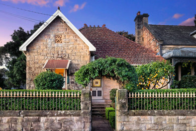 Design ideas for a mid-sized modern two-storey house exterior in Sydney with stone veneer, a gable roof, a tile roof and a red roof.