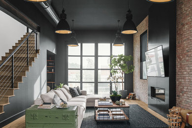 Inspiration for a large industrial open concept family room with black walls, a ribbon fireplace, a metal fireplace surround, a wall-mounted tv, medium hardwood floors and brown floor.