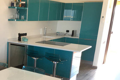 Foto di una cucina costiera con lavello integrato, ante di vetro, ante turchesi, top in quarzite, elettrodomestici in acciaio inossidabile e top bianco