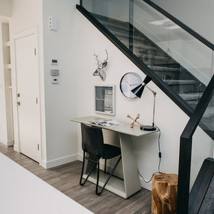 エドモントンの小さいモダンスタイルのおしゃれな書斎 (白い壁、無垢フローリング、標準型暖炉、漆喰の暖炉まわり、自立型机、茶色い床) の写真