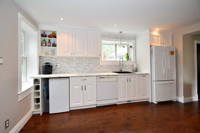 Inspiration for a mid-sized farmhouse l-shaped laminate floor and brown floor eat-in kitchen remodel in Toronto with a single-bowl sink, raised-panel cabinets, white cabinets, laminate countertops, white backsplash, mosaic tile backsplash, white appliances and white countertops