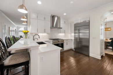 Mid-sized minimalist u-shaped dark wood floor and brown floor kitchen photo in Cleveland with an undermount sink, shaker cabinets, white cabinets, quartz countertops, white backsplash, subway tile backsplash, stainless steel appliances and white countertops