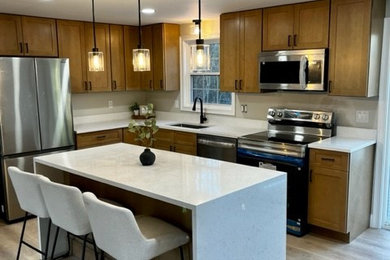 Inspiration for a mid-sized transitional l-shaped laminate floor and brown floor eat-in kitchen remodel in Boston with an undermount sink, shaker cabinets, medium tone wood cabinets, quartz countertops, white backsplash, quartz backsplash, stainless steel appliances, an island and white countertops