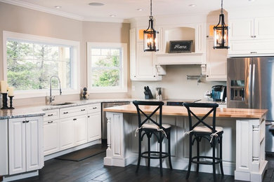 Arts and crafts u-shaped dark wood floor kitchen photo in Other with an undermount sink, raised-panel cabinets, white cabinets, wood countertops, stainless steel appliances and an island