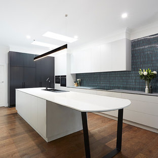 Идея дизайна: линейная кухня с кладовкой, накладной раковиной, фасадами с декоративным кантом, белыми фасадами, мраморной столешницей, фартуком из плитки кабанчик, черной техникой, полом из фанеры и островом