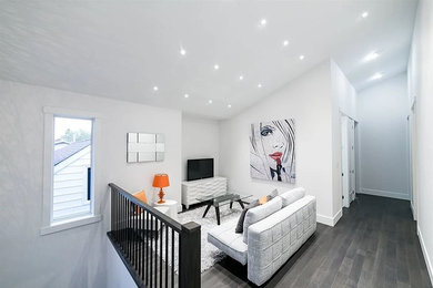 Family room - transitional medium tone wood floor and gray floor family room idea in Edmonton with white walls and a tv stand
