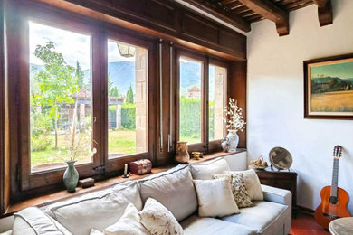Imagen de salón con rincón musical cerrado y blanco y madera de estilo de casa de campo de tamaño medio de obra con paredes blancas, suelo de baldosas de terracota, estufa de leña, marco de chimenea de ladrillo, televisor independiente, suelo rojo y vigas vistas