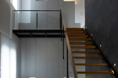 Idées déco pour un escalier contemporain avec des marches en bois, un garde-corps en verre et du lambris.
