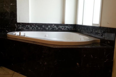 他の地域にある広いコンテンポラリースタイルのおしゃれなマスターバスルーム (ドロップイン型浴槽、黒いタイル、磁器タイル、白い壁、磁器タイルの床、ベージュの床) の写真
