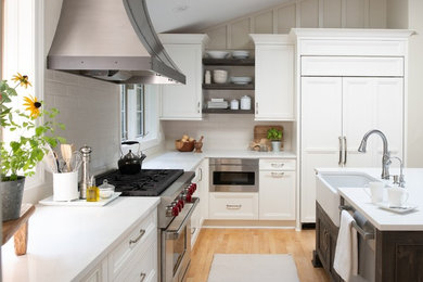 This is an example of a mid-sized transitional u-shaped eat-in kitchen in Minneapolis with a farmhouse sink, flat-panel cabinets, white cabinets, quartz benchtops, beige splashback, subway tile splashback, stainless steel appliances, with island and white benchtop.