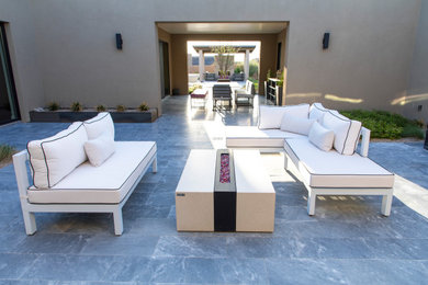 Design ideas for a large modern courtyard patio in Phoenix with a fire feature, natural stone pavers and no cover.