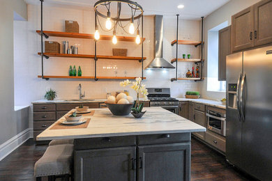 Inspiration for a large industrial l-shaped dark wood floor and brown floor enclosed kitchen remodel in St Louis with an undermount sink, shaker cabinets, marble countertops, white backsplash, subway tile backsplash, stainless steel appliances, an island and medium tone wood cabinets