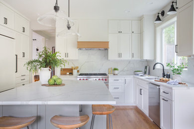Large country u-shaped light wood floor and brown floor open concept kitchen photo in Seattle with an undermount sink, shaker cabinets, white cabinets, quartz countertops, white backsplash, quartz backsplash, paneled appliances, an island and white countertops