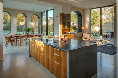 Идея дизайна: большая угловая кухня в стиле рустика с обеденным столом, плоскими фасадами, фасадами цвета дерева среднего тона, столешницей из бетона, островом и серой столешницей