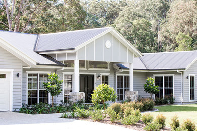 This is an example of a country one-storey grey house exterior in Sunshine Coast with concrete fiberboard siding, a clipped gable roof and a metal roof.