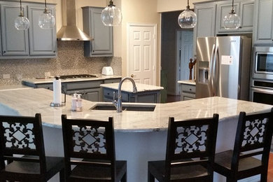 Inspiration for a large contemporary u-shaped medium tone wood floor eat-in kitchen remodel in Dallas with an undermount sink, raised-panel cabinets, gray cabinets, granite countertops, multicolored backsplash, mosaic tile backsplash, stainless steel appliances and an island