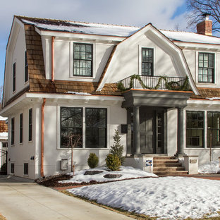 Удачное сочетание для дизайна помещения: двухэтажный фасад дома белого цвета в классическом стиле с облицовкой из цементной штукатурки и мансардной крышей - самое интересное для вас
