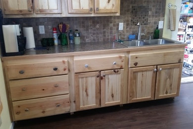 Example of a country kitchen design in Boise with shaker cabinets, distressed cabinets, beige backsplash, stone tile backsplash and paneled appliances