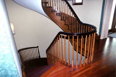 Ejemplo de escalera curva clásica grande con escalones de madera y contrahuellas de madera