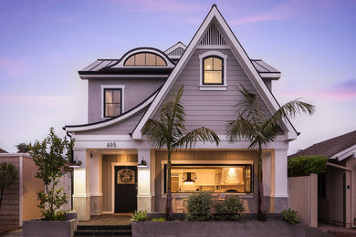 Design ideas for a beach style two-storey grey house exterior in Orange County with wood siding and a metal roof.
