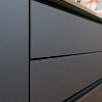 Matt black glass handleless kitchen with stainless steel worktop