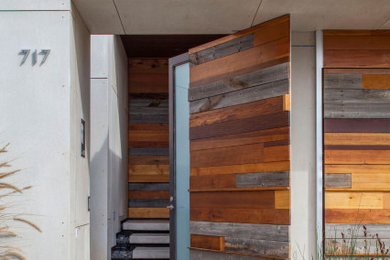 This is an example of a contemporary front door in Los Angeles with a pivot front door and a medium wood front door.