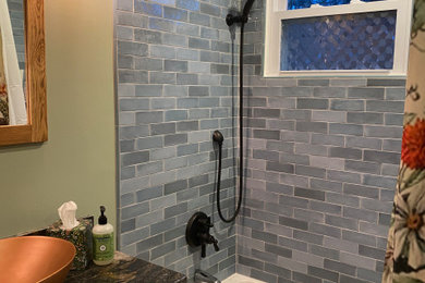 Example of a mid-sized mountain style master blue tile and ceramic tile wood-look tile floor, brown floor and single-sink bathroom design in Bridgeport with shaker cabinets, distressed cabinets, a two-piece toilet, green walls, a vessel sink, granite countertops, black countertops and a freestanding vanity