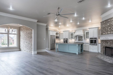 Inspiration for a large transitional l-shaped dark wood floor and brown floor kitchen remodel in Austin with a farmhouse sink, shaker cabinets, white cabinets, solid surface countertops, white backsplash, ceramic backsplash, stainless steel appliances, an island and black countertops