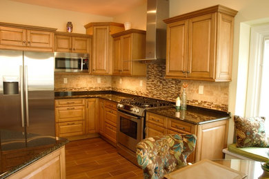 Example of a mid-sized transitional l-shaped ceramic tile eat-in kitchen design in Other with a farmhouse sink, raised-panel cabinets, medium tone wood cabinets, granite countertops, beige backsplash, ceramic backsplash, stainless steel appliances and an island
