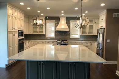 Mid-sized transitional u-shaped medium tone wood floor and brown floor open concept kitchen photo in Cincinnati with a farmhouse sink, glass-front cabinets, white cabinets, quartz countertops, gray backsplash, subway tile backsplash, stainless steel appliances, an island and white countertops
