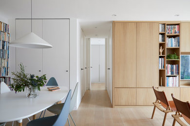 This is an example of a small modern living room in London with white walls and light hardwood flooring.