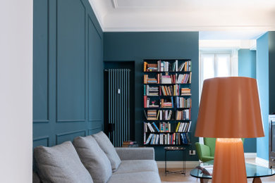 Idee per un grande soggiorno chic aperto con libreria, pareti blu, parquet chiaro, TV a parete, pavimento beige, boiserie e tappeto