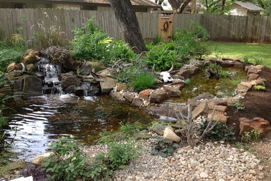 This is an example of a mid-sized traditional shade backyard gravel water fountain landscape in Austin.