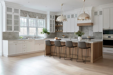 Inspiration for a large transitional light wood floor kitchen remodel in New York with a farmhouse sink, shaker cabinets, white cabinets, quartzite countertops, stone slab backsplash, paneled appliances and an island