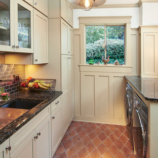 クリーブランドの小さいおしゃれな家事室 (シングルシンク、落し込みパネル扉のキャビネット、御影石カウンター、左右配置の洗濯機・乾燥機、ベージュのキャビネット、白い壁、テラコッタタイルの床、オレンジの床) の写真