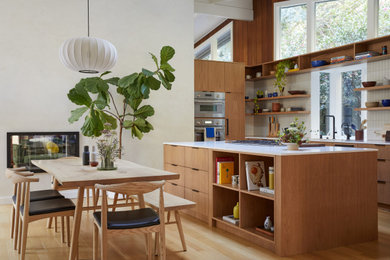 Eat-in kitchen - mid-sized 1950s u-shaped light wood floor, brown floor and exposed beam eat-in kitchen idea in San Francisco with an undermount sink, flat-panel cabinets, medium tone wood cabinets, marble countertops, white backsplash, ceramic backsplash, paneled appliances, an island and beige countertops