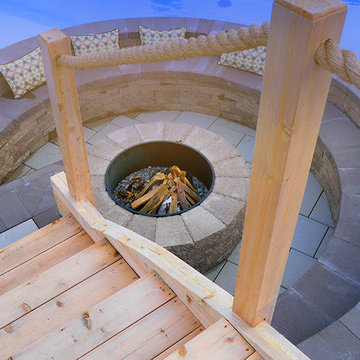 Pool with a firepit by Exact Landscapes