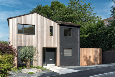 Inspiration for a medium sized and brown scandinavian two floor front house exterior in Surrey with wood cladding, a pitched roof, a tiled roof, a red roof and board and batten cladding.
