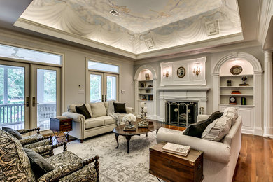 Example of a classic formal and open concept medium tone wood floor living room design in Charleston with gray walls, a standard fireplace and a wood fireplace surround